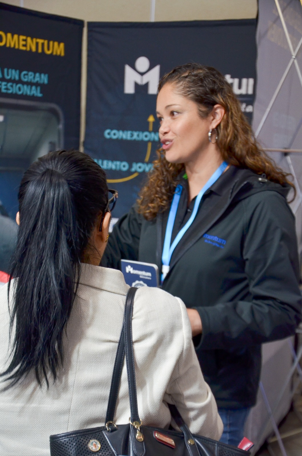 Ejecutiva de Uxara Agency conversando con una asistente en un evento profesional
